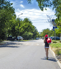 Young attractive Santa walks around the city with a bag of gifts.