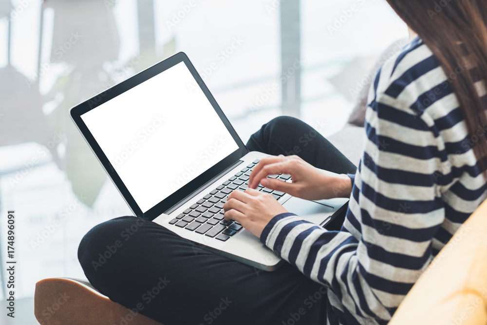 Poster woman in casual cloth cross leg sitting on sofa and using laptop computer with blank screen,mock up 