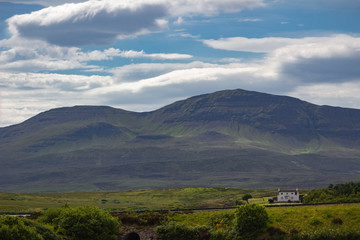 Gorgeous landscape on the Isle of Skye with Mountain range and a small white country house in Scotland.
