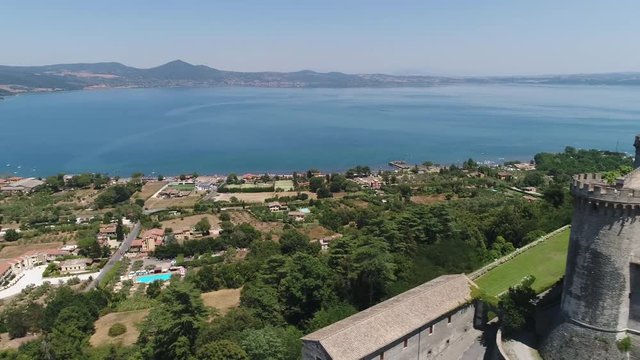 A guard tower of the Orsini castle near. The glassy surface of lake Bracciano.