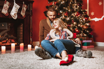 A couple of lovers resting by the fireplace in the Christmas room. Feet in woolen socks warming in winter time.