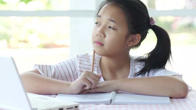 Beautiful asian girl thinking and writing to notebook on the table 4k 1