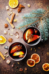 Two mugs of christmas mulled wine or gluhwein with spices and orange slices on rustic table top view. Traditional drink on winter holiday. Vintage toned.