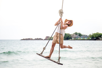 girl stands on a swing on the beach of Thailand