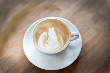 A beautiful cup of hot late art on the wooden table