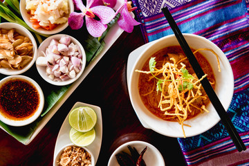 A beautiful set of Khao Soi, local northern food of Thailand. Khao soi is checken with curry with crispy noodle on top. Eat with traditional side dishes.