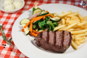 Grilled steak, french fries and vegetables. rosemary and spices