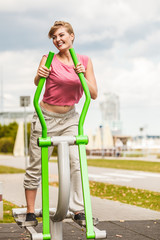 Active woman exercising on elliptical trainer.