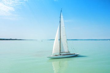A view from a ship to bright Balaton lake water and a white yacht on sunny summer day, Hungary. - obrazy, fototapety, plakaty
