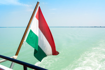 Hungarian flag at the cruise ship with bright light blue water of Balaton lake at the background Hungary.