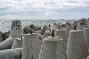 An embankment of Baltic sea at the city Baltiysk on cloudy summer day, a view to the gray seascape, waves and big stone blocks at pier, the most western point of Russia, Kaliningrad region.