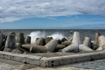 An embankment of Baltic sea at the city Baltiysk on cloudy summer day, a view to the gray seascape, waves and big stone blocks at pier, the most western point of Russia, Kaliningrad region.