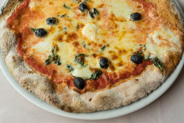 Pizza with buffalo mozzarella,tomatoes,olives and basil,view from above
