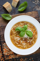 Above view of soup with lentil, pasta and addition of parmesan cheese, vertical shot