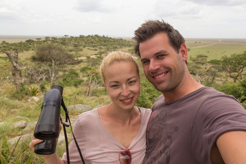 Casual adult couple taking selfie on african wildlife safari in Serengeti national park, Tanzania, Africa.