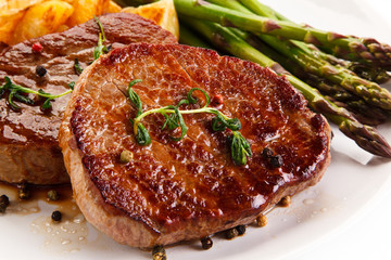 Grilled beef steaks,chips and asparagus on white background 