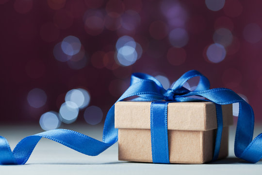 Small gift box or present against magic bokeh background. Holiday greeting card for Christmas or New Year.