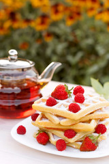Belgian waffles with strawberries and raspberries. Tea drinking.