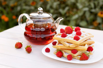 Belgian waffles with strawberries and raspberries. Tea drinking.