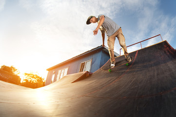 Teen skater hang up over a ramp on a skateboard in a skate park