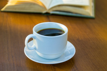 Cup of coffee and book on wooden table