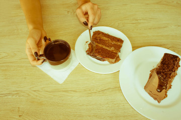 Female hand holding on long spoon a piece of cake at table in ca
