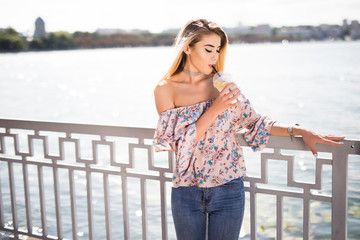 Portrait of young attractive woman sitting on promenade and drink lemonade at summer day