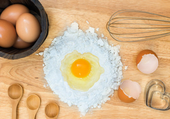Top view composition flour with egg and ingredients for homemade bakery on wooden background