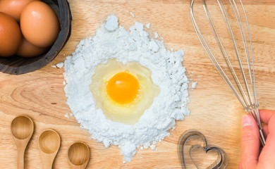 Top view composition flour with egg and ingredients for homemade bakery on wooden background
