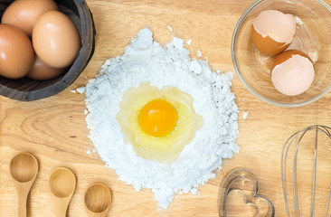 Top view composition flour with egg and ingredients for homemade bakery on wooden background