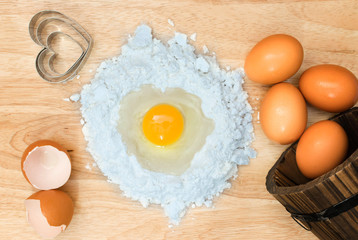 Top view composition flour with egg and ingredients for homemade bakery on wooden background