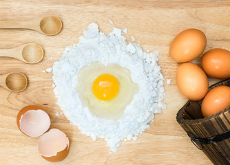 Top view composition flour with egg and ingredients for homemade bakery on wooden background