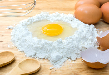 flour with egg and ingredients for homemade bakery on wooden background