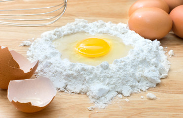 flour with egg and ingredients for homemade bakery on wooden background