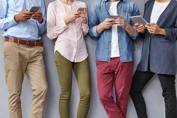 People community, team work and cooperation concept. Group of people use electronic devices for creating new project, share ideas. Four colleagues discuss business plan, search information online