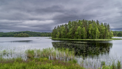 Beautiful view of a green island in the Lakeland in central Finland, near Rantasalmi, under a dramatic sky