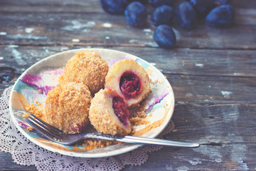 Plum dumplings on colorful plate on wooden background