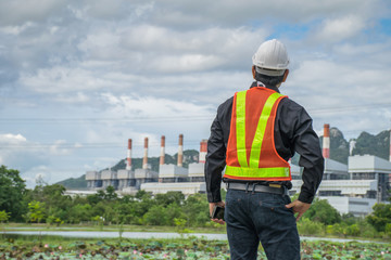 Engineer with a coal power plant in the background.