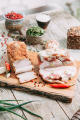 homemade bacon cut into thin pieces with the salt and spices on a wooden Board