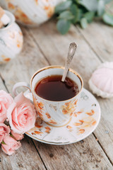 tea set in composition with flowers and marshmallows. Coffee mug on a saucer, a teapot and a sugar bowl. Filmed in the interior