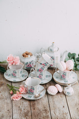 tea set in composition with flowers and marshmallows. Coffee mug on a saucer, a teapot and a sugar bowl. Filmed in the interior