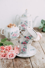 tea set in composition with flowers and marshmallows. Coffee mug on a saucer, a teapot and a sugar bowl. Filmed in the interior