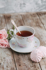 tea set in composition with flowers and marshmallows. Coffee mug on a saucer, a teapot and a sugar bowl. Filmed in the interior