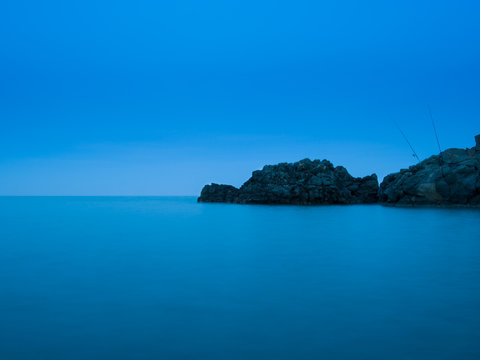 Sea landscape at sunset with fishing poles