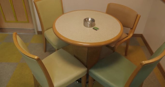Chairs around table with ashtray in smoking room