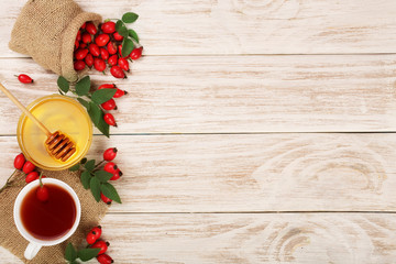 tea with rose hips and honey on white wooden background with copy space for your text. Top view