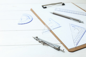 triangle, compass, ruler, protractor on white wooden desk