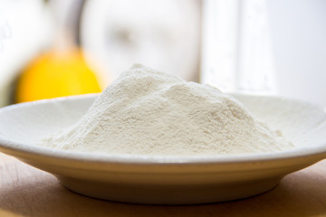 Wheat flour in a white porcelain plate on the table