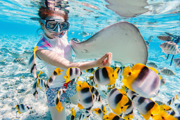 Woman snorkeling with tropical fish - obrazy, fototapety, plakaty