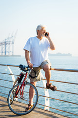 Fototapeta premium Portrait of retirement handsome senior man on phone with sea background